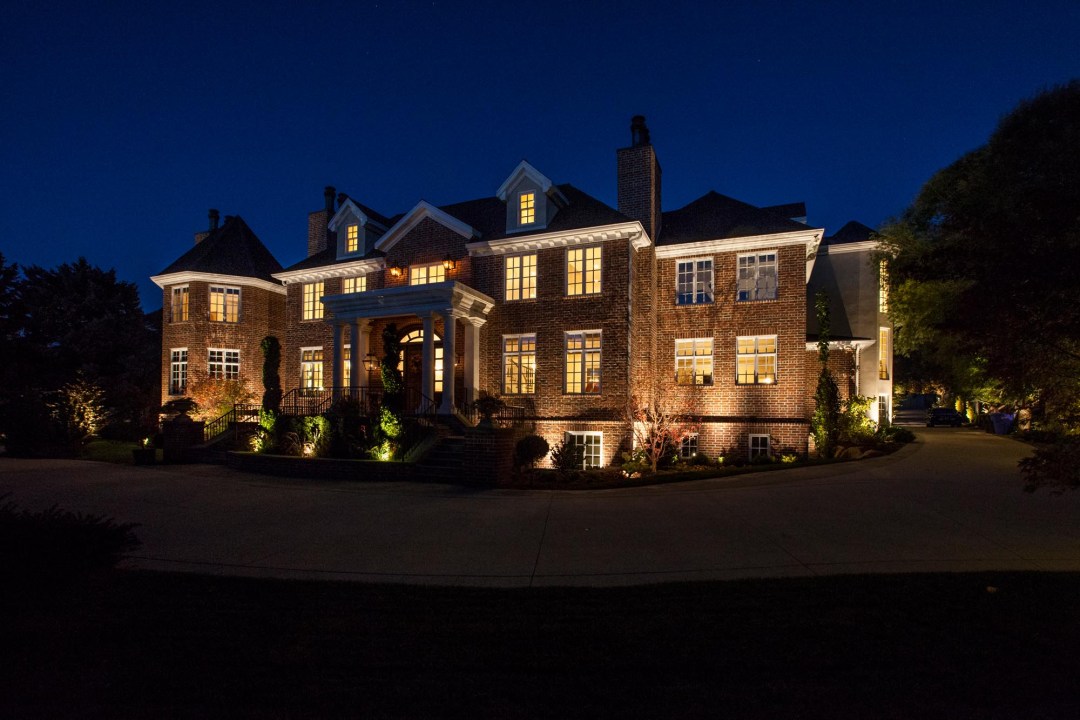 A beautifully lit mansion at night, emphasizing its architectural features, with lights provided by Night Vision Lighting & Electric.<br />