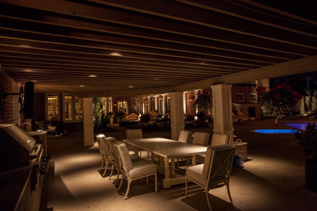 A nighttime patio featuring a dining table and chairs, illuminated by night vision lighting.