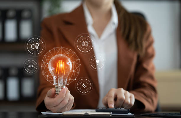 A businesswoman in a suit holds a light bulb, symbolizing ideas for Night Vision Lighting & Electric.